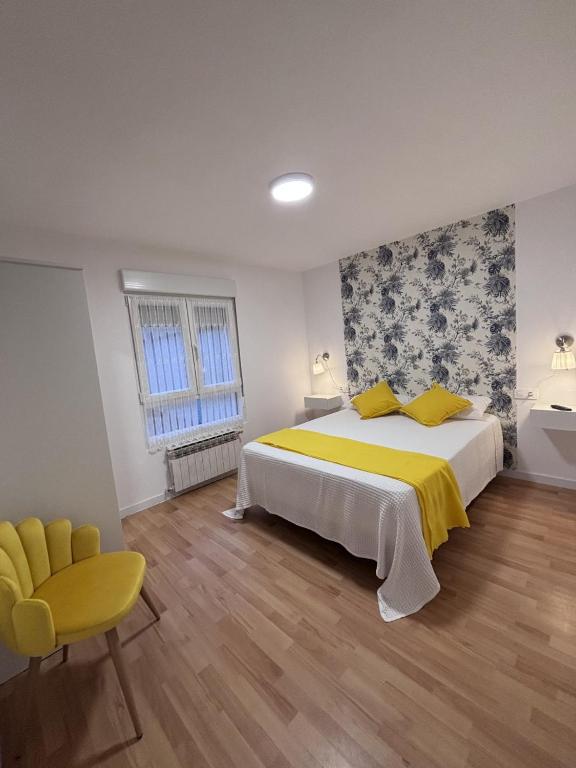 a bedroom with a large bed and a yellow chair at El Rinconin I in Cangas de Onís