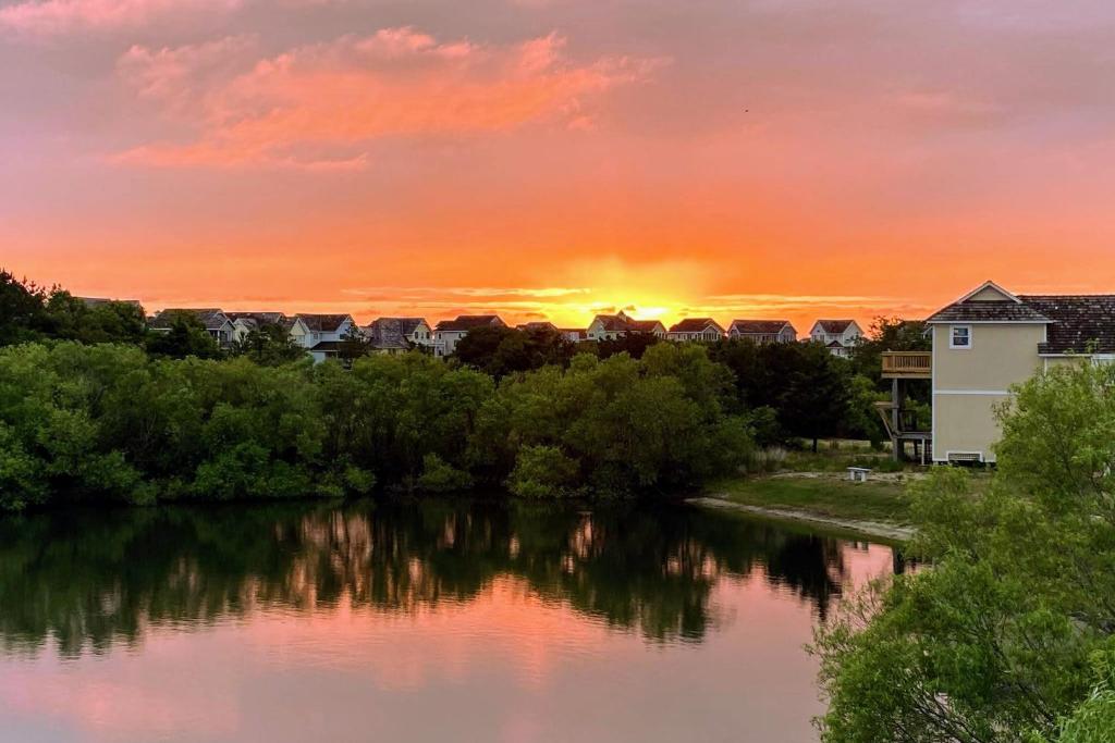 a sunset over a river with trees and buildings at Gone Fishin in Nags Head