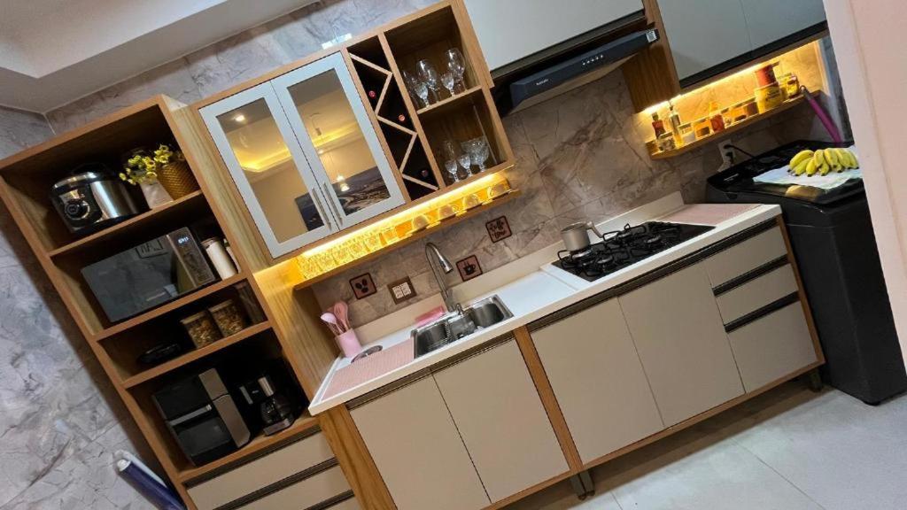 a kitchen with white cabinets and a stove top oven at Quarto para mulheres em Cond Orla Recreio Prainha in Rio de Janeiro