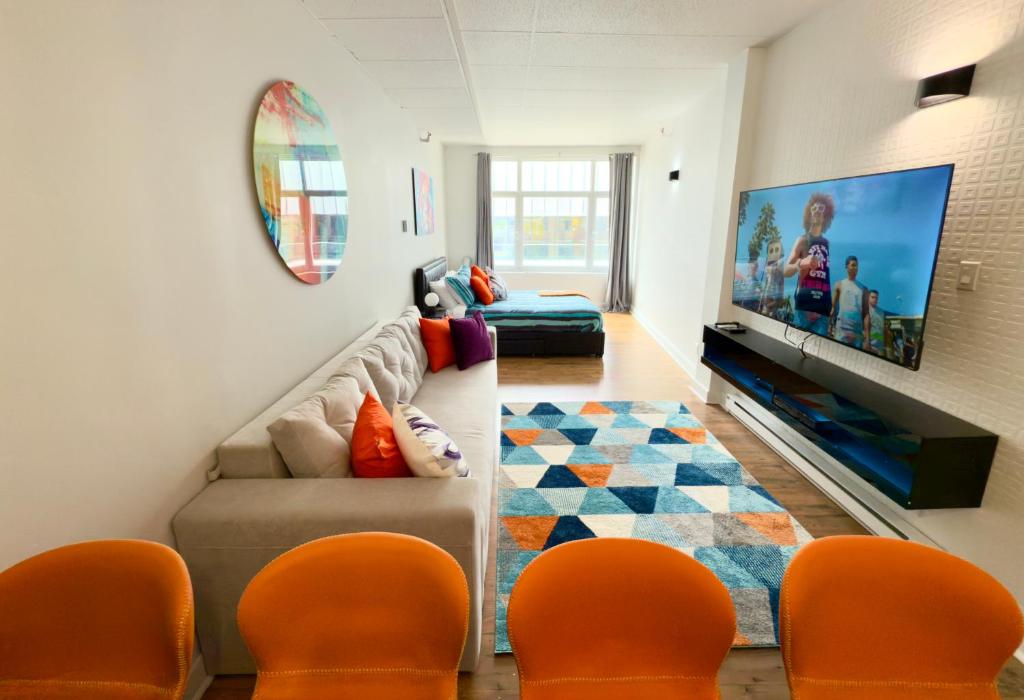 een woonkamer met oranje stoelen en een flatscreen-tv bij Refuge Urbain Quebec - Lofts de la Cité in Québec
