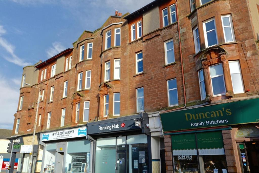 a large brick building on a city street with stores at 2 bedroom first floor flat- Bonnie Stays in Troon