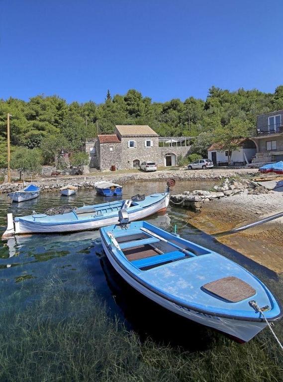three boats are docked in the water near a house at Villa Nada in Banići