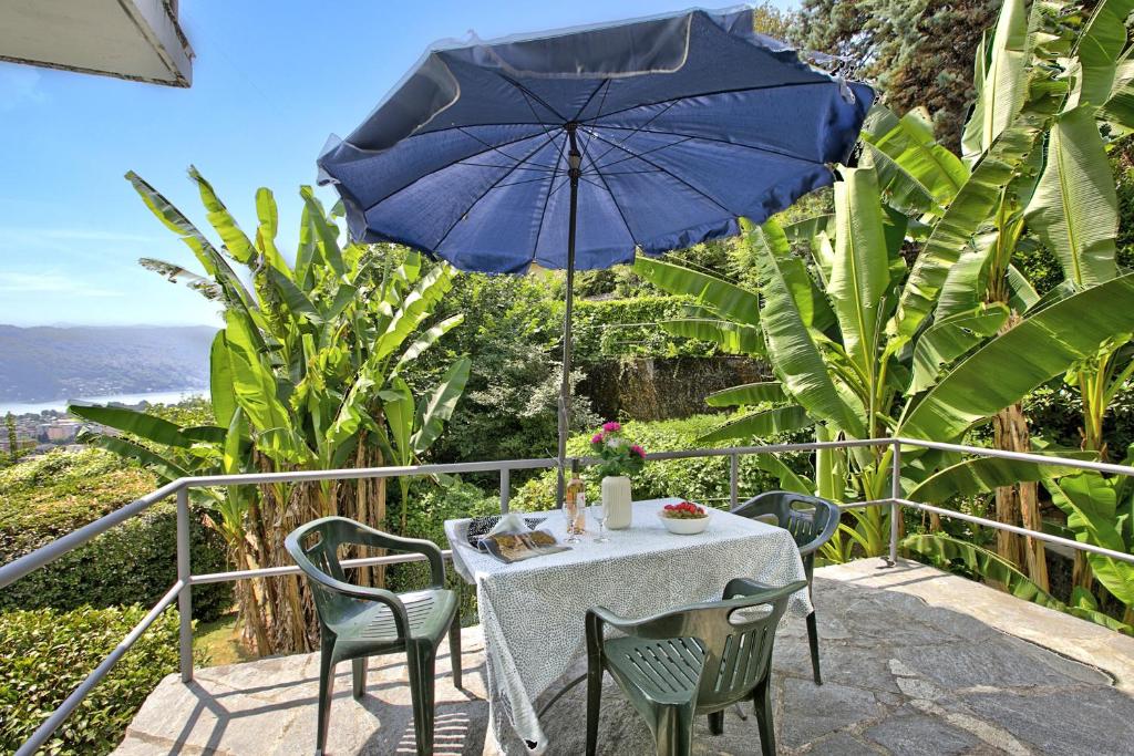 una mesa y sillas con una sombrilla azul en el balcón en Apartment View And Pool - Happy Rentals, en Agno