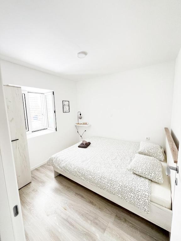 a white bedroom with a bed and a window at House9 in Kotor