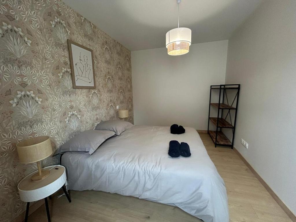 een slaapkamer met een bed met twee schoenen erop bij Côté Pyrénées - Lourdes in Lourdes