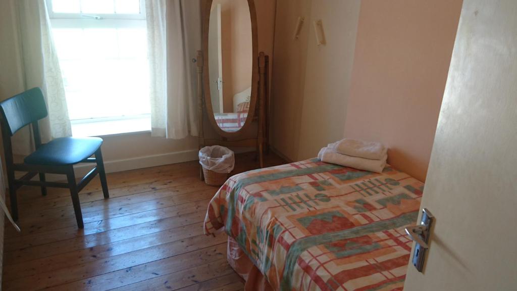 1 dormitorio con cama, silla y espejo en Eilymaes, en Portmagee