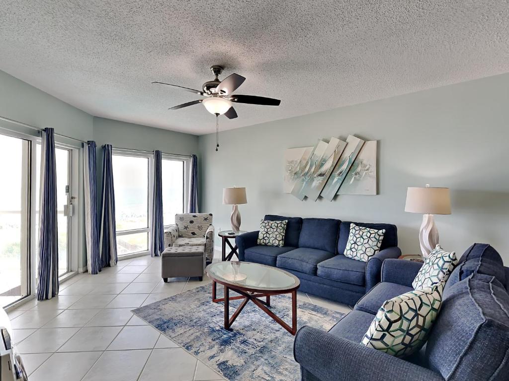 Una sala de estar con un sofá azul y una mesa. en Emerald Isle #302, en Pensacola Beach