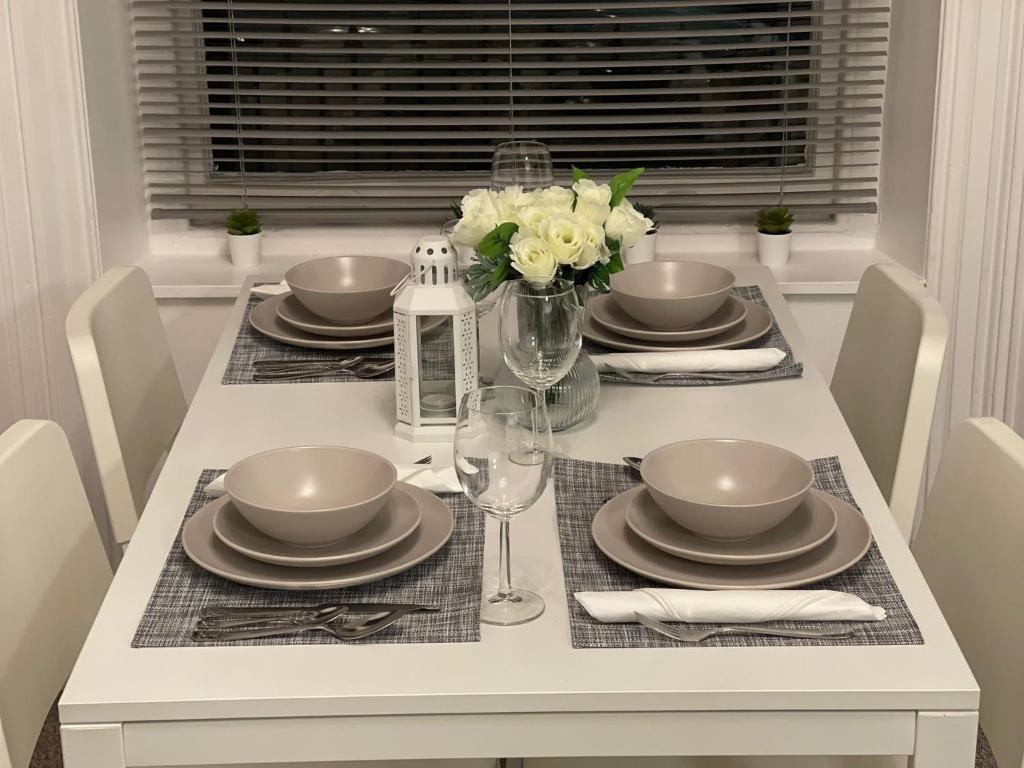 a dining room table with plates and glasses and flowers at Abchuch chambers in Bournemouth