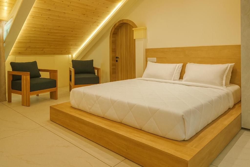 a bedroom with a large bed and two chairs at Brookfield in Pālampur