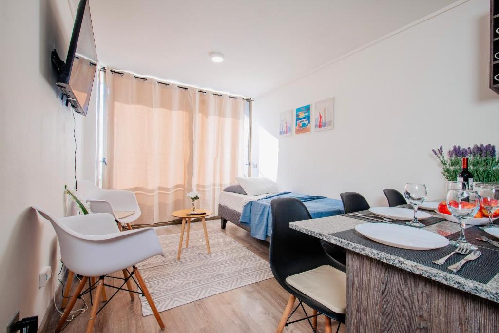 a room with a bed and a table and chairs at Loica Host - Departamentos amoblados a pasos del metro in Santiago