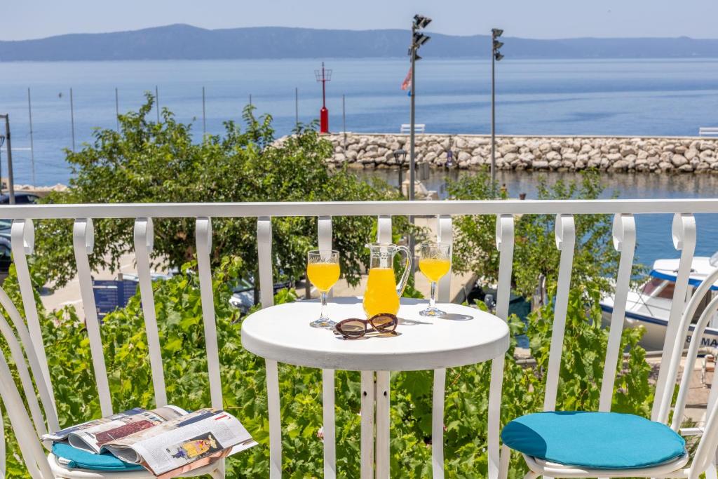 a table with glasses on a balcony with the ocean at Apartments Amfora 2 in Podgora