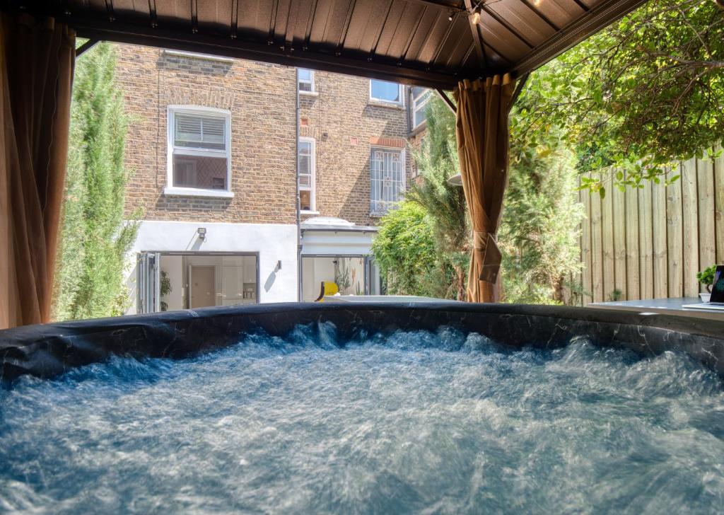 a hot tub in a backyard with water in it at London Queen's Park with cinema & gaming room in London