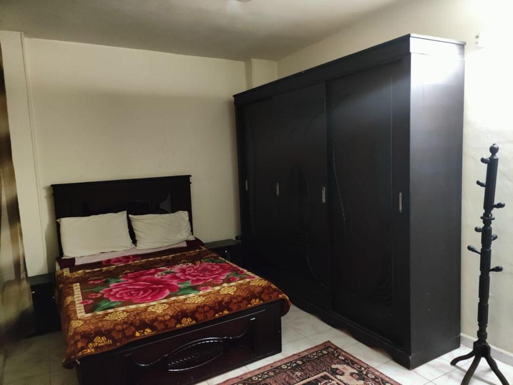 a bedroom with a bed with a large black headboard at شارع العريش هرم in Banī Ghālib