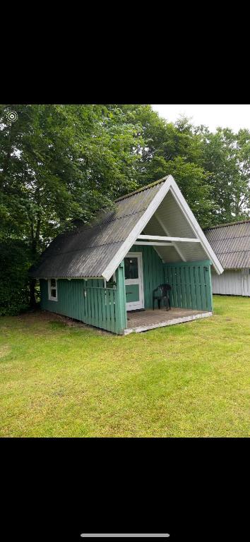 a green house with a gambrel roof in a yard at Tarm Camping in Tarm