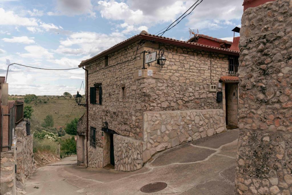 an old stone building with a stone wall at Casa Rural La Mansión de la Toba in La Toba