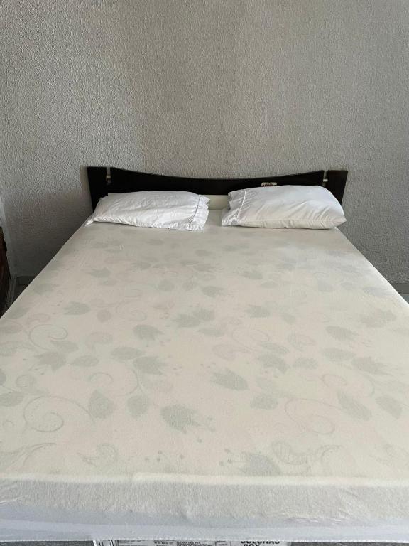 a bed with two pillows on top of it at Suíte Central in Palmas