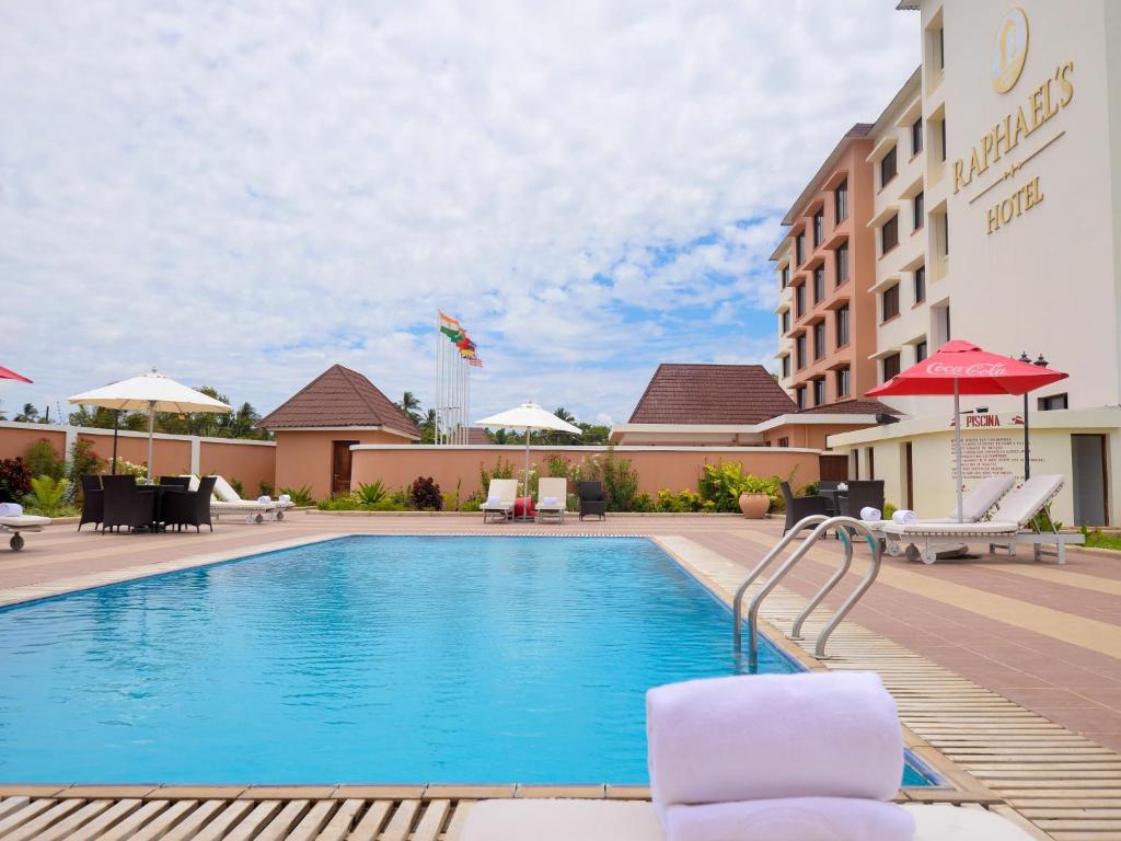 uma piscina num hotel com cadeiras e guarda-sóis em Raphael's Hotel em Pemba