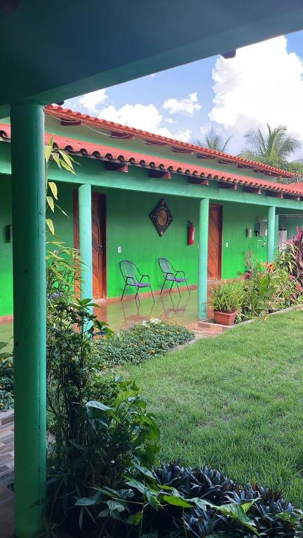 a green house with two chairs in front of it at Pousada Mãe e Filhas in Mateiros
