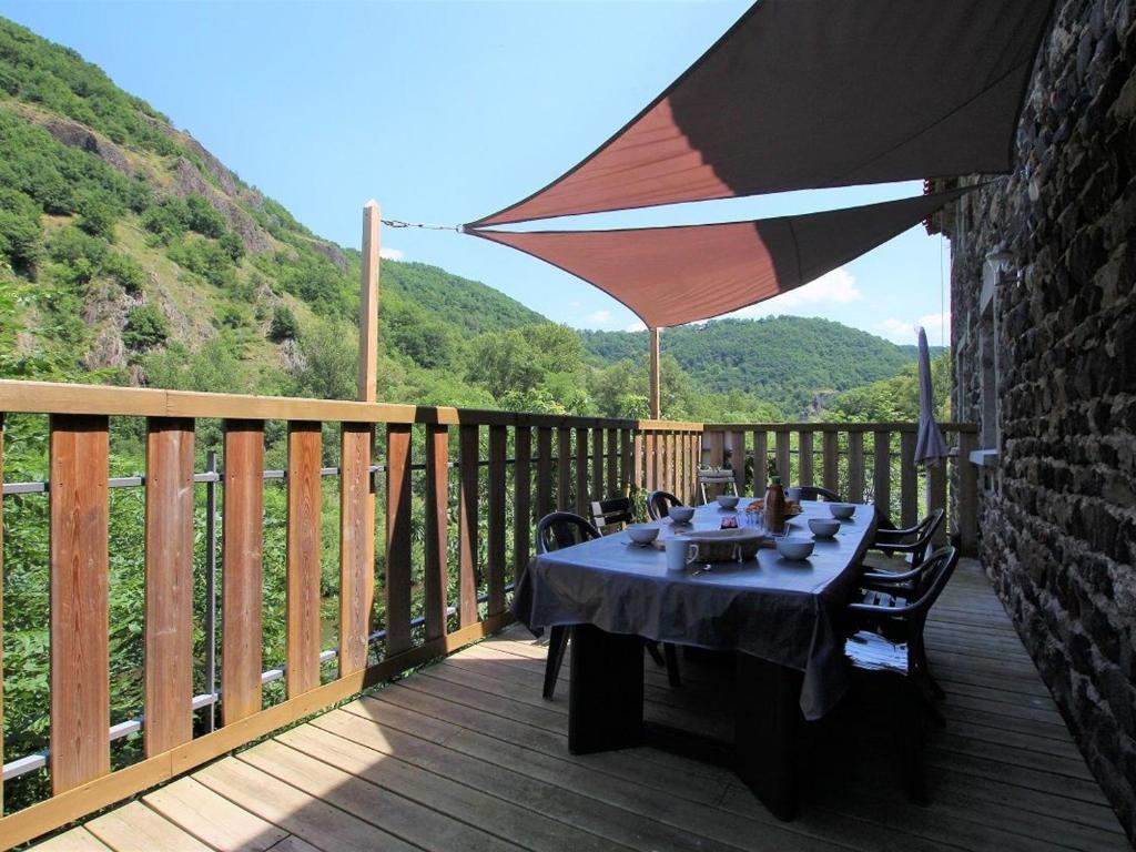 - une table sur une terrasse en bois avec un parasol dans l'établissement Gîte spacieux avec terrasse surplombant rivière, idéale pour pêche et sports d’eau, tout inclus - FR-1-582-17, à Saint-Julien-des-Chazes