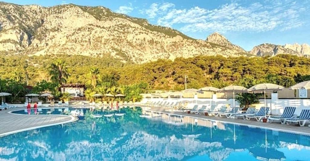 a swimming pool with chairs and mountains in the background at Magic Sun Hotel in Beldibi