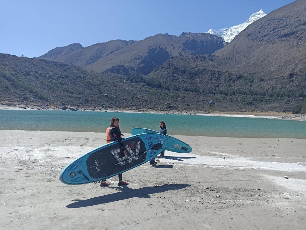 Dos mujeres de pie en una playa sosteniendo tablas de surf en CARAZ Miski Wasi, en San Antonio