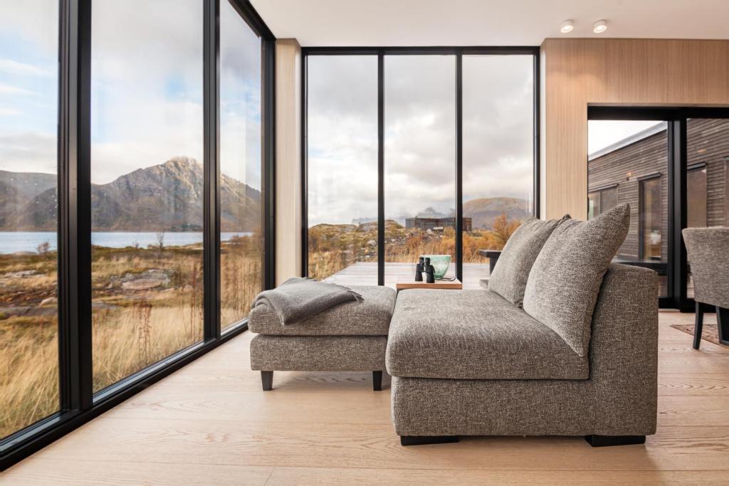 a living room with a chair and large windows at New lodge at seaside, near Henningsvær Lofoten in Kleppstad