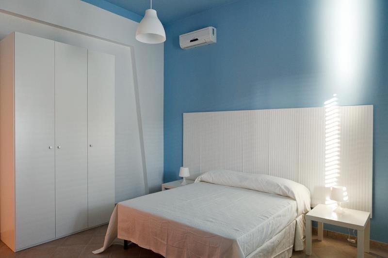 1 dormitorio con cama blanca y pared azul en Casa Letizia, en Porto Cesareo