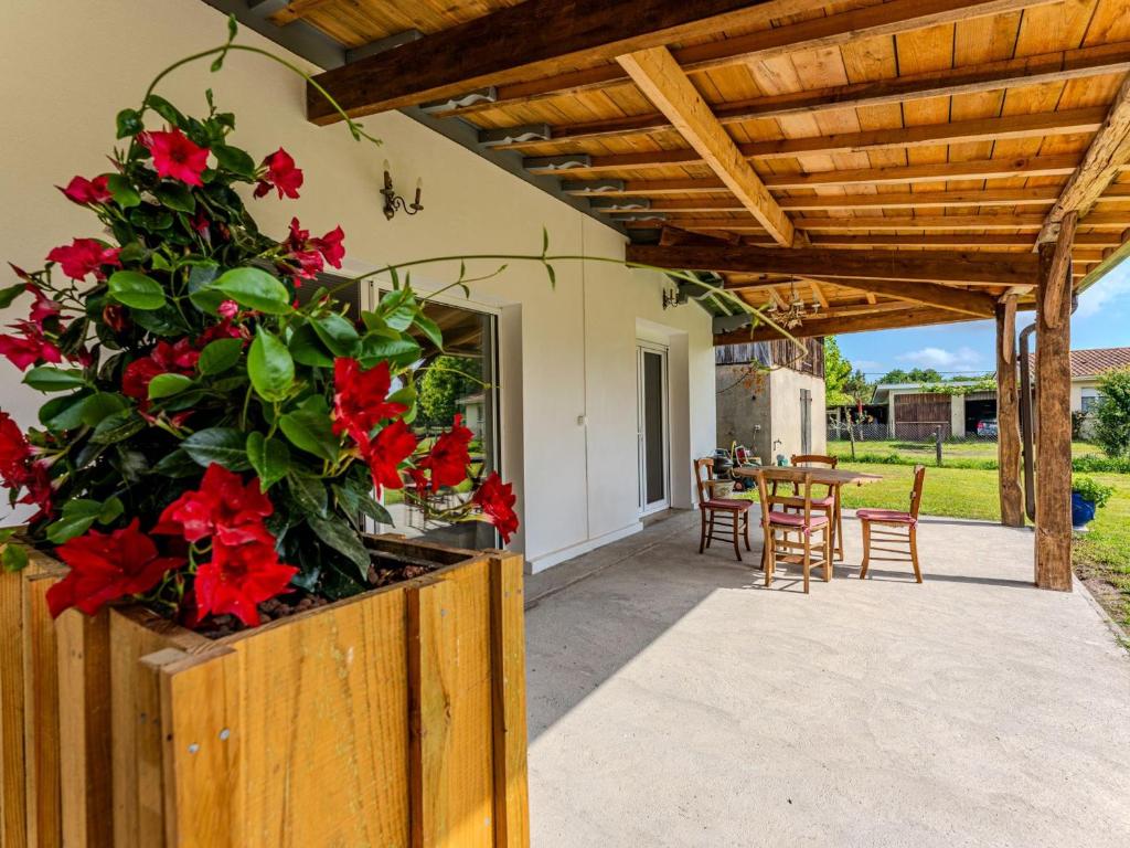 eine Terrasse mit roten Blumen, einem Tisch und Stühlen in der Unterkunft Maison mitoyenne 4 pers., animaux acceptés, terrasse à Sanguinet - FR-1-521-239 in Sanguinet