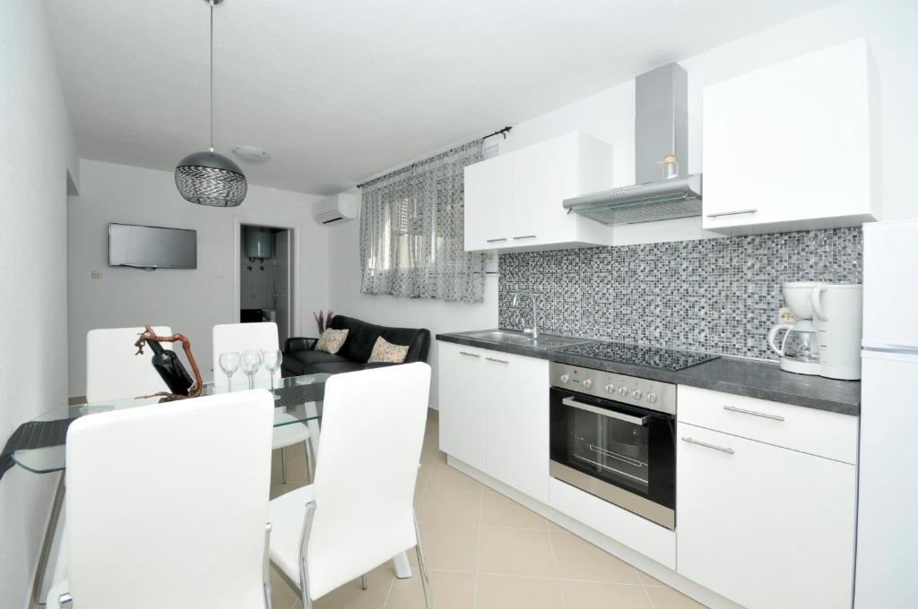 a kitchen with white cabinets and a table and chairs at Apartmani Mijatović in Trogir