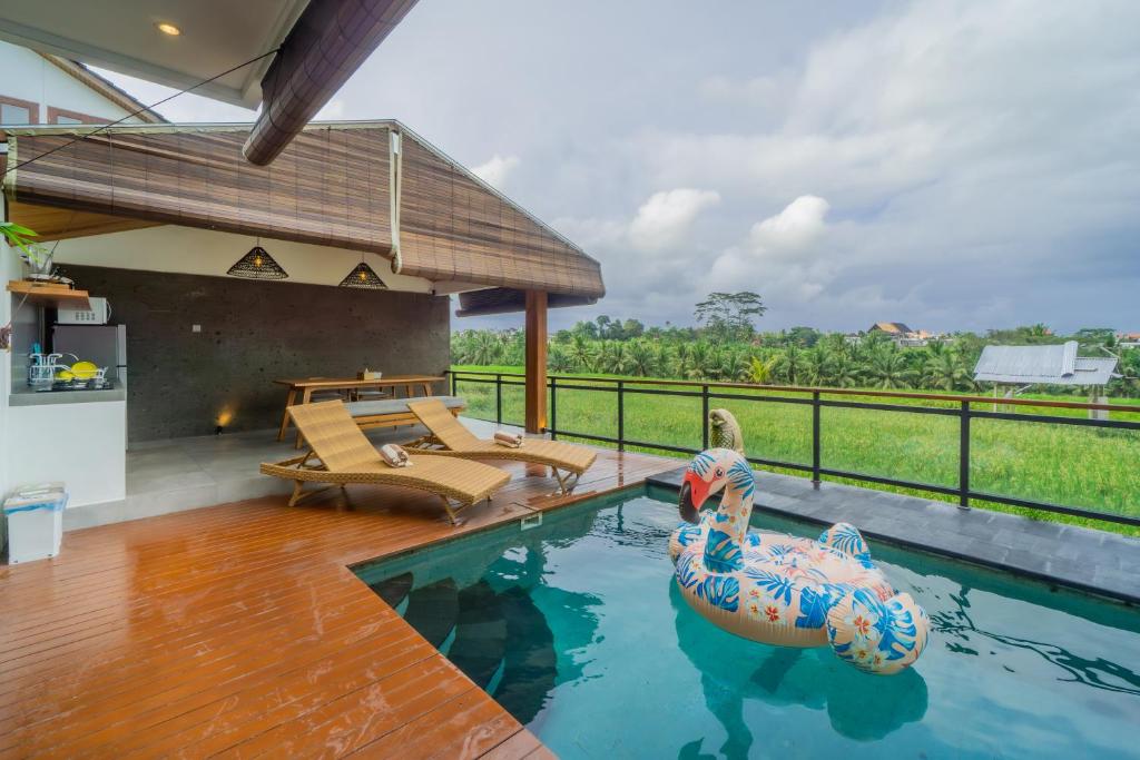 an outdoor swimming pool with an inflatable pool noodle in a house at Kairos Villa Ubud by Omkara Experience in Ubud