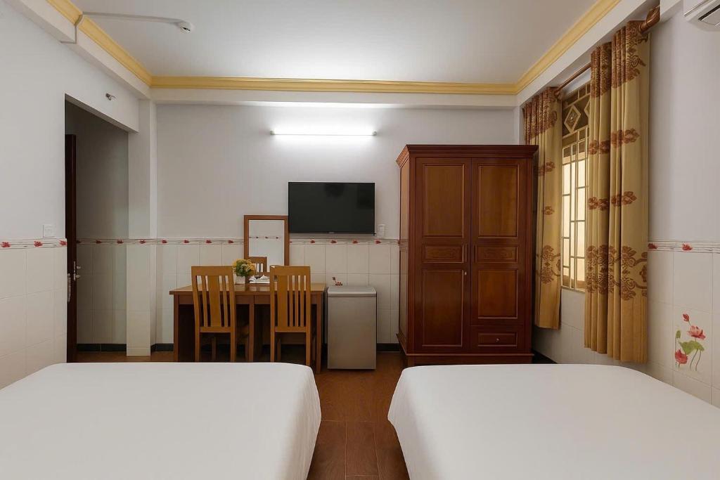 a room with two beds and a table with a television at Diamond Hotel CMT8 - Center SaiGon in Ho Chi Minh City