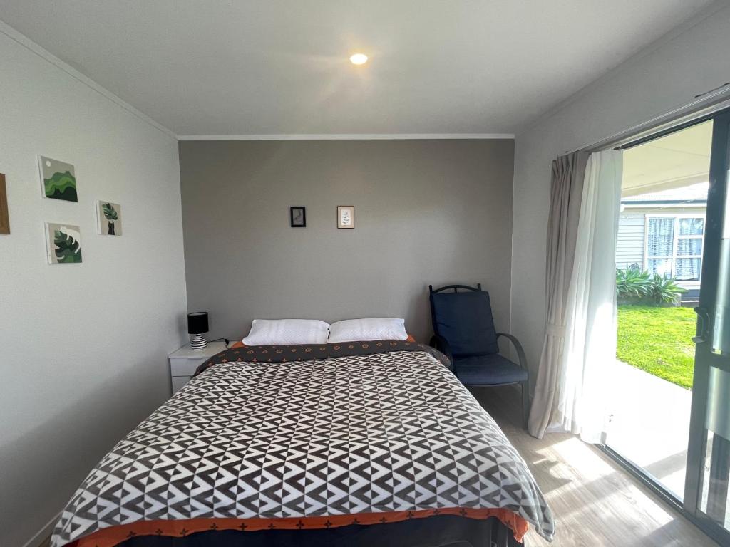 a bedroom with a bed and a large window at Self check-in sleepout with bathroom in Te Miro