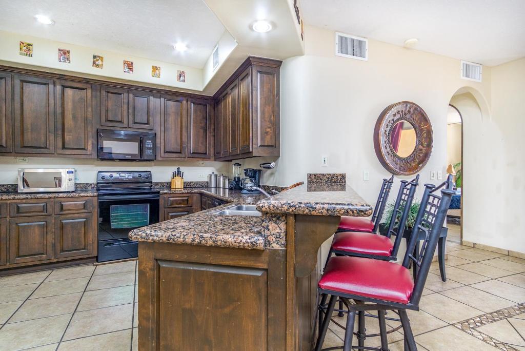 a kitchen with wooden cabinets and a counter with red chairs at Bella Sirena in Puerto Peñasco
