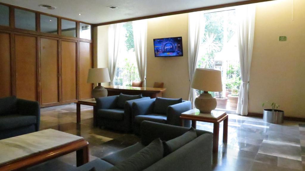 A spacious lounge with dark upholstered seating, marble floors and tall windows.