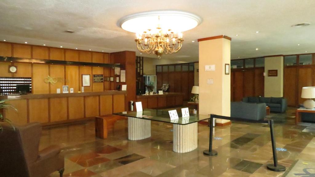 A spacious, wood-paneled lobby with a reception counter, chandelier, and waiting seating.