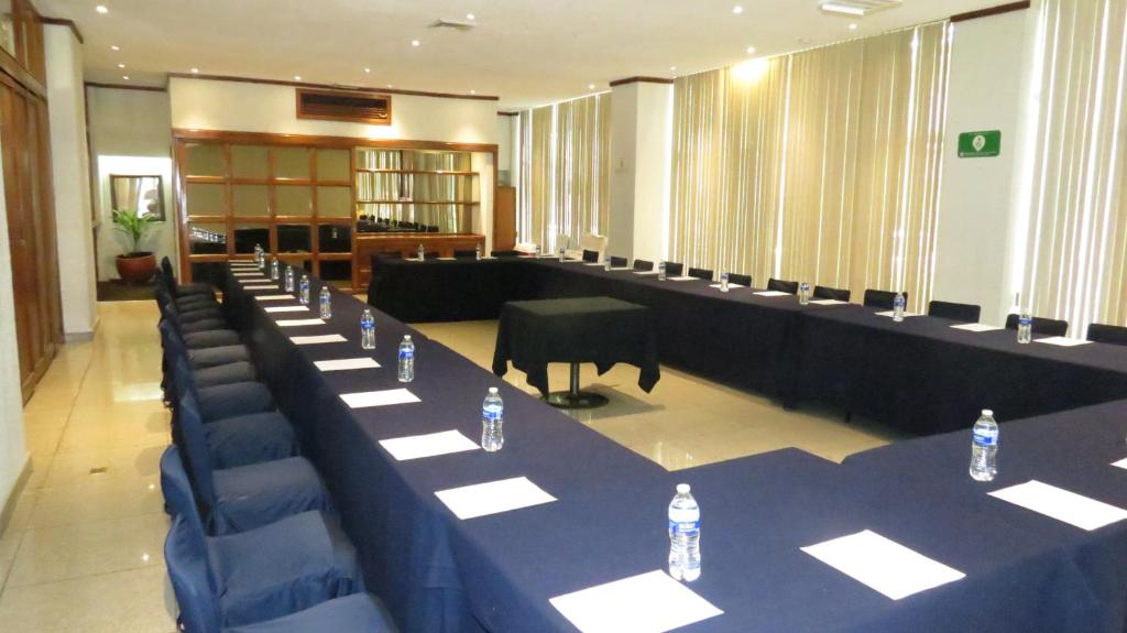 A bright conference room prepared with long tables, chairs, bottled water, and notepaper.