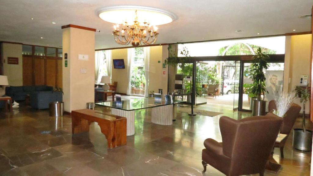 A formal lobby with a central glass table, chandelier and garden-facing entrance.
