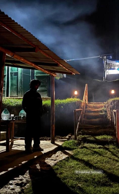 a man standing in front of a fire at night at Neytiiri camping & stay in Kūkkāl
