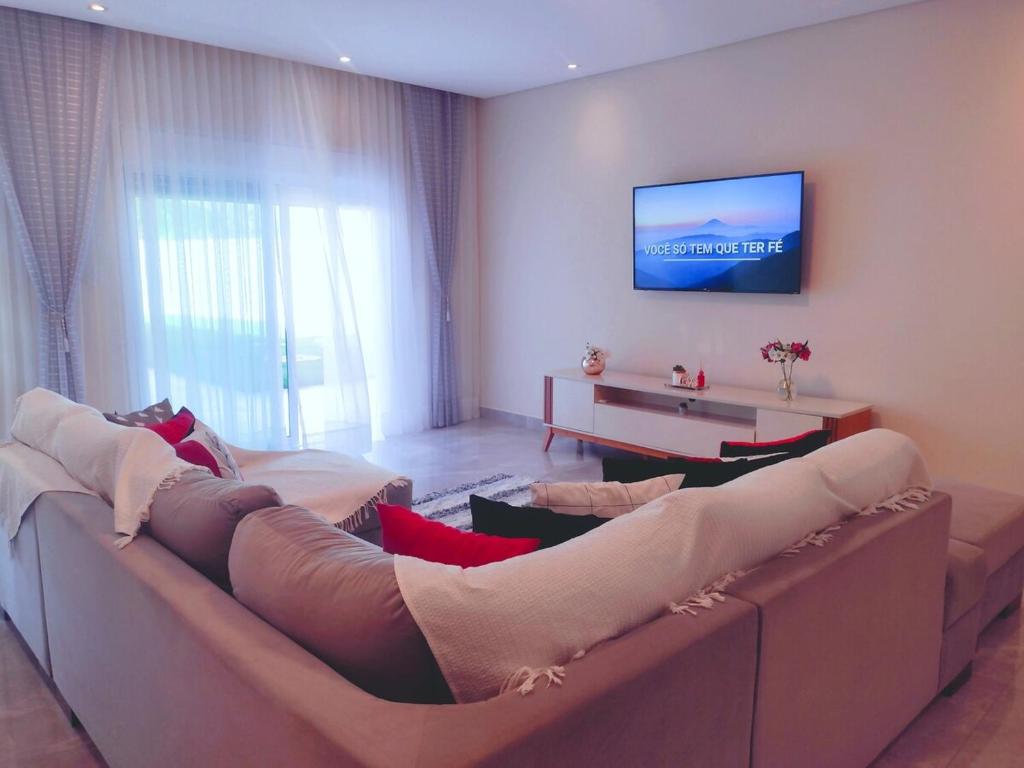 a living room with a couch and a tv on a wall at House in Iguape in Iguape