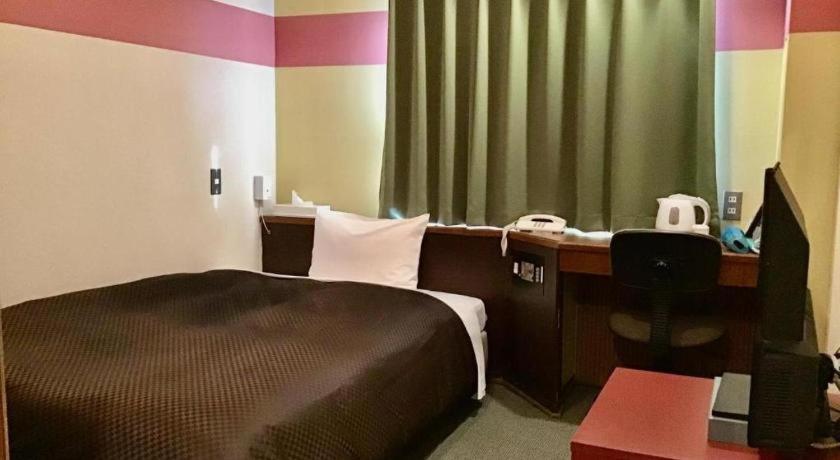 ein Schlafzimmer mit einem Bett und einem Schreibtisch mit einem Computer in der Unterkunft Mimatsu Annex in Mito