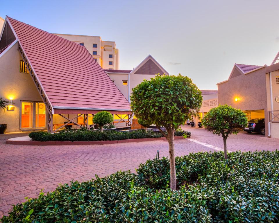 a building with a red roof and two trees at Courtyard Hotel Sandton in Johannesburg