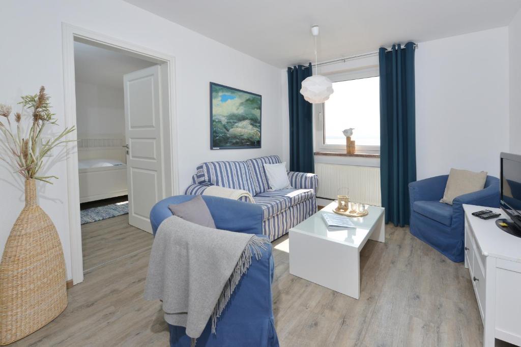 ein Wohnzimmer mit blauen Sofas und einem TV in der Unterkunft Ferienwohnung Boddenzander in Breege