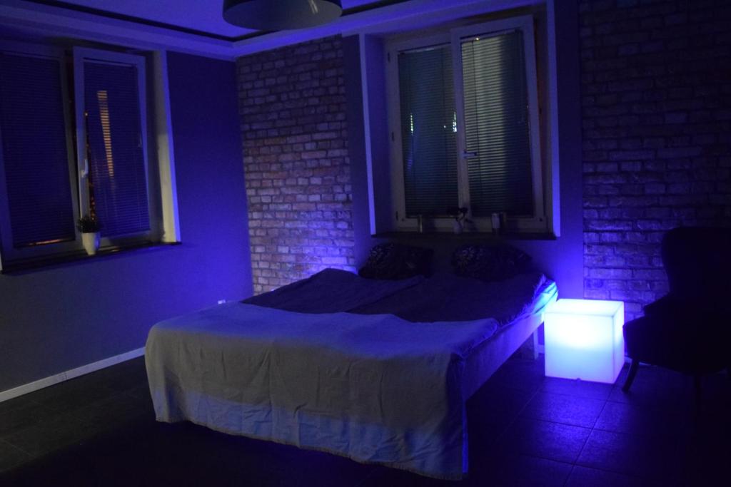 - une chambre avec un lit et une lumière bleue dans l'établissement Apartament na doby, à Poznań