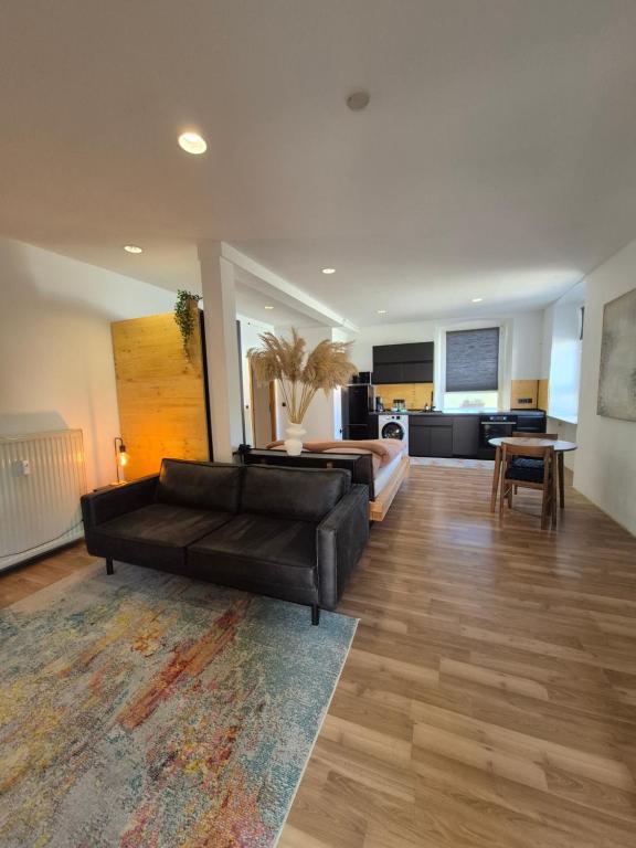 a living room with a black couch and a kitchen at Apartment #1 in Olsbrücken