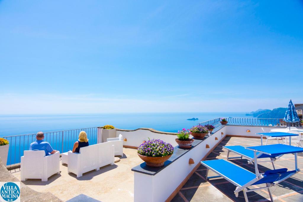 Due persone sedute su un balcone che guarda l'oceano di Villa Antica Macina a Positano