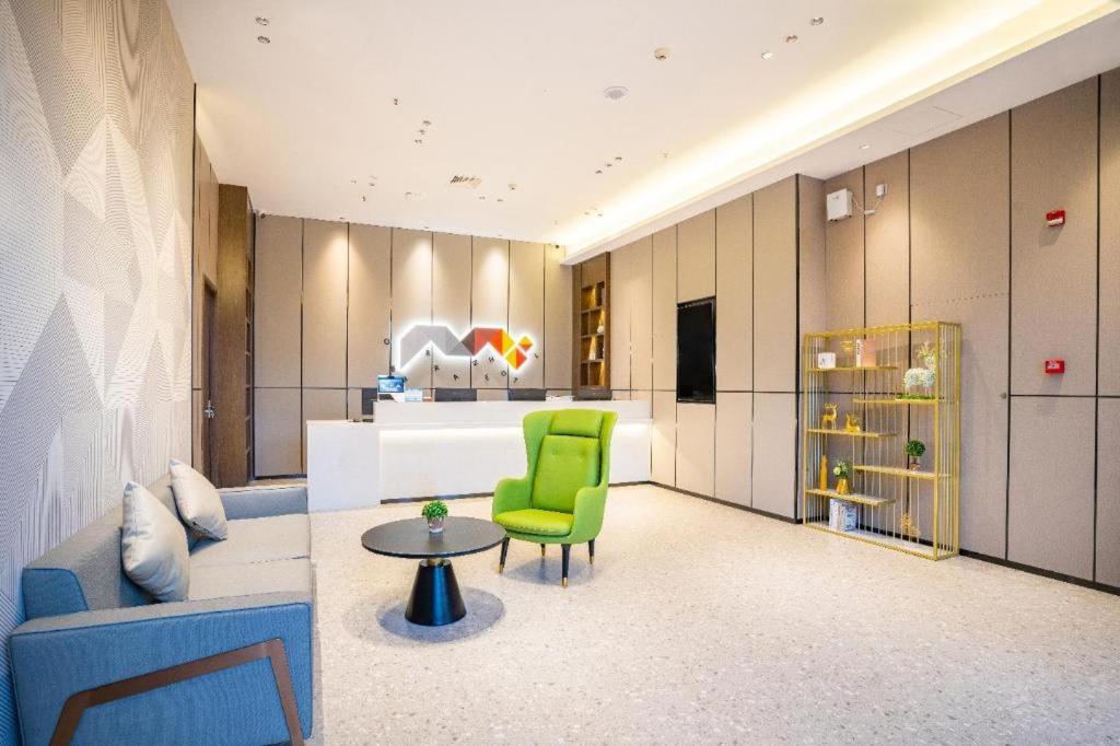 a living room with a green chair and a table at Borrman Hotel Nanning Anji Wanda Plaza Sulu Metro Station in Nanning