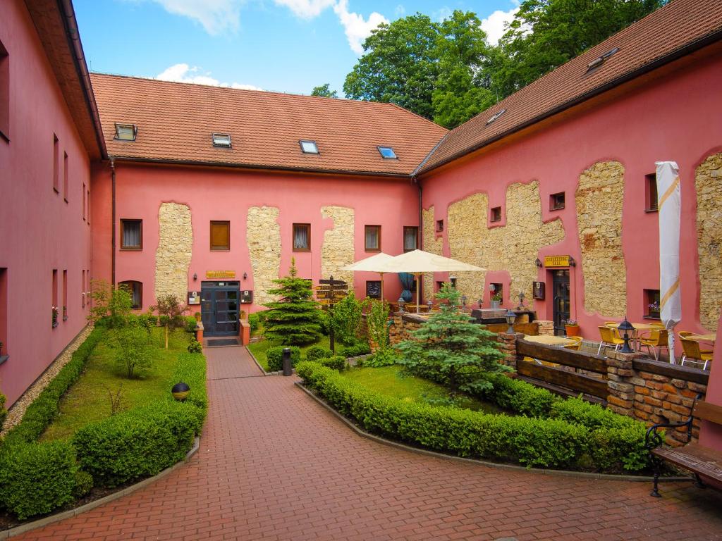 einen Innenhof eines rosa Gebäudes mit einer Terrasse in der Unterkunft Hotel Stary Pivovar in Prag