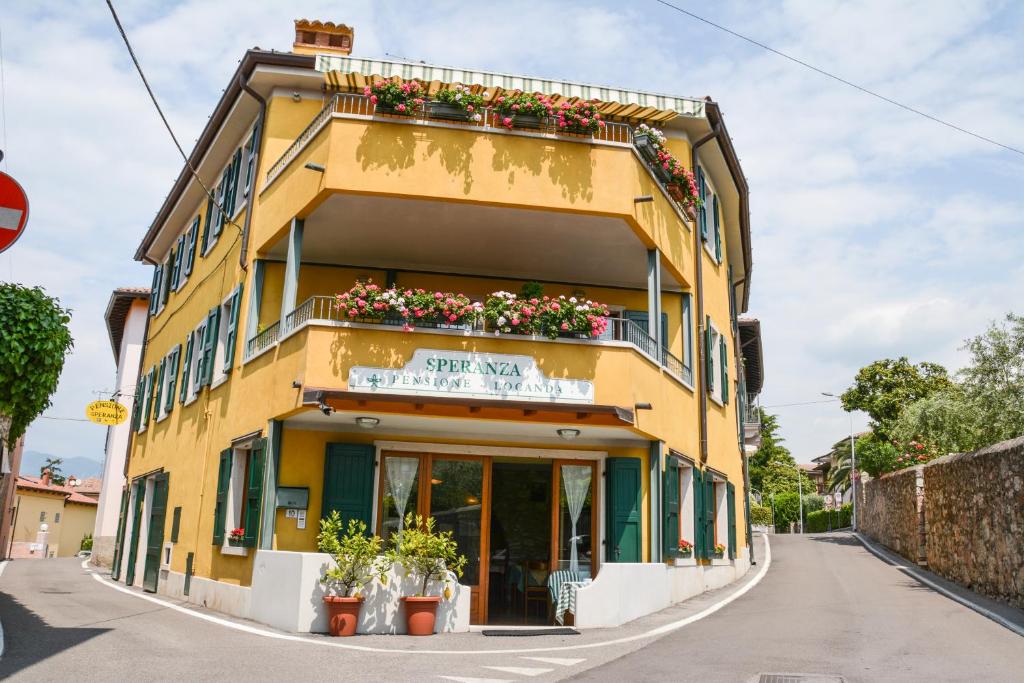 un edificio amarillo con macetas de flores a un lado. en Locanda Speranza, en Torri del Benaco