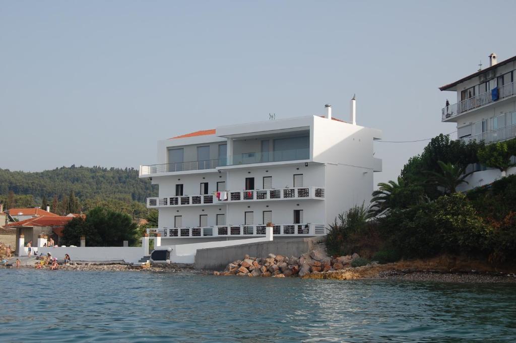 a large white building next to a body of water at Asmini Studios in Pefki