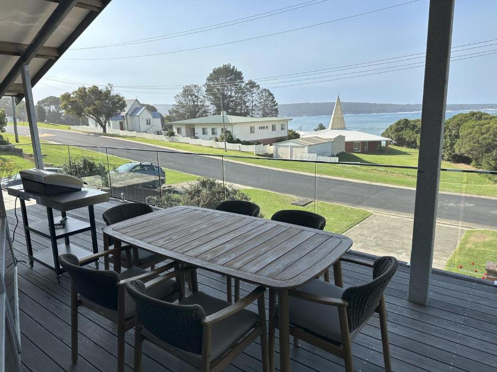 a table and chairs on a porch with a view of a street at Eden Niu in Eden